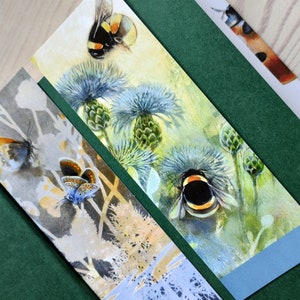 May include: Three bookmarks with watercolor illustrations of insects and flowers. The first bookmark features a blue butterfly on a light gray background. The second bookmark features a bumblebee on a blue and green background. The third bookmark features a bumblebee on a yellow and green background.