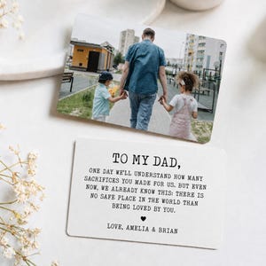 May include: A personalized photo card with a picture of a father walking with two children. The card below has the text "TO MY DAD" and a heartfelt message. The card is a sentimental gift.