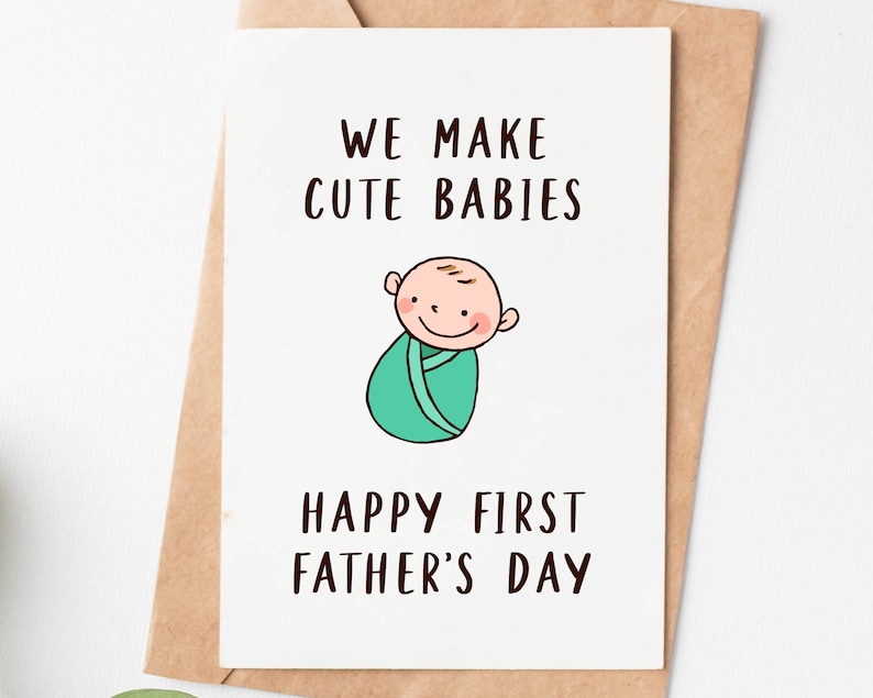 May include: A white card with the text "We make cute babies" and a cartoon drawing of a baby in a swaddle. The card also says "Happy First Father's Day".