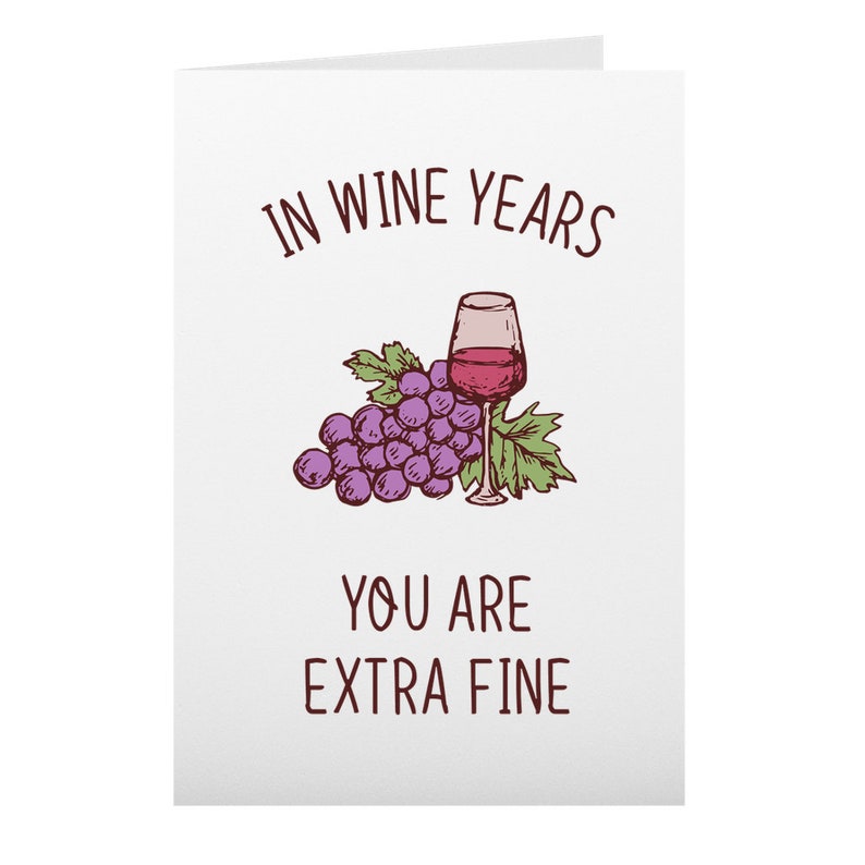 May include: A white card with the text "In wine years you are extra fine" in brown lettering. A cartoon illustration of a bunch of purple grapes and a glass of red wine is above the text.