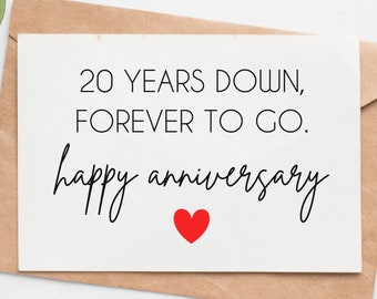 Puede incluir: Tarjeta blanca con el texto negro "20 YEARS DOWN, FOREVER TO GO." Debajo, las palabras "happy anniversary" en cursiva, con un corazón rojo. La tarjeta está dentro de un sobre marrón.