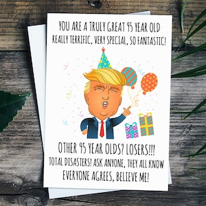 May include: A humorous birthday card featuring a cartoon illustration of Donald Trump wearing a party hat and pointing. The card reads "You are a truly great 95 year old really terrific, very special, so fantastic! Other 95 year olds? Losers!!! Total disasters! Ask anyone, they all know everyone agrees, believe me!"