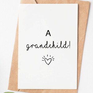 May include: A white card with black text that reads "A grandchild!" with a small heart and radiating lines above it.