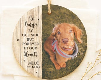 Può includere: Ornamento commemorativo per animali domestici in legno rotondo con una foto di un cane marrone. L'ornamento presenta il testo "No longer by our side but forever in our hearts" e il nome "Milo" con gli anni 2014-2025.