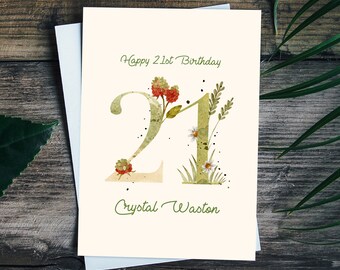 Può includere: Un biglietto bianco con testo verde che dice "Happy 21st Birthday". Il numero 21 è scritto in verde con fiori e foglie ad acquerello. Il nome "Crystal Weston" è scritto in verde sotto il numero.