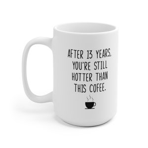 May include: White ceramic coffee mug with black text that reads "After 13 years. You're still hotter than this coffee."  A small black and white illustration of a steaming cup of coffee is below the text.