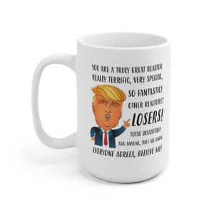 May include: White ceramic mug with a cartoon image of a man with blonde hair and a red tie. The text on the mug reads: "You are a truly great realtor really terrific, very special, so fantastic! Other realtors? Losers! Total disasters! Ask anyone, they all know everyone agrees, believe me!"