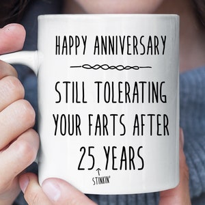 May include: White ceramic coffee mug with black text that reads "Happy Anniversary - Still Tolerating Your Farts After 25 Years - Stinkin'"