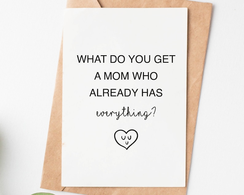 May include: A white card with black text that reads "What do you get a mom who already has everything?" with a small heart with a face drawn inside.