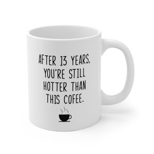 May include: White ceramic coffee mug with black text that reads "After 13 years, you're still hotter than this coffee."  A small black and white illustration of a coffee cup with steam is below the text.