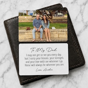 May include: A personalized wallet card with a photo of a father and daughter, resting on a dark brown leather wallet. The card has the text "To My Dad" and a heartfelt message from "Amelia".