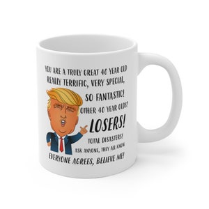 May include: White ceramic coffee mug with a humorous illustration of a man with a blonde comb-over and a red tie. The text on the mug reads "You are a truly great 40 year old really terrific, very special, so fantastic! Other 40 year olds? Losers! Total disasters! Ask anyone, they all know everyone agrees, believe me!"