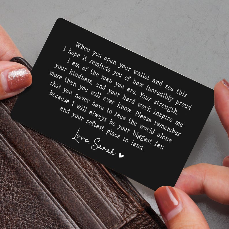 May include: A black wallet card with white text held by a person. The card has a heartfelt message that reads, "When you open your wallet and see this..." The card is a sentimental gift.