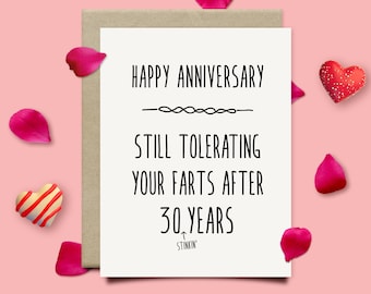 May include: A white card with black text that reads "Happy Anniversary" with a decorative line below. The text continues with "Still Tolerating Your Farts After 30 Years" with the word "Stinkin'" below. The card is on a pink background with red hearts and pink rose petals.
