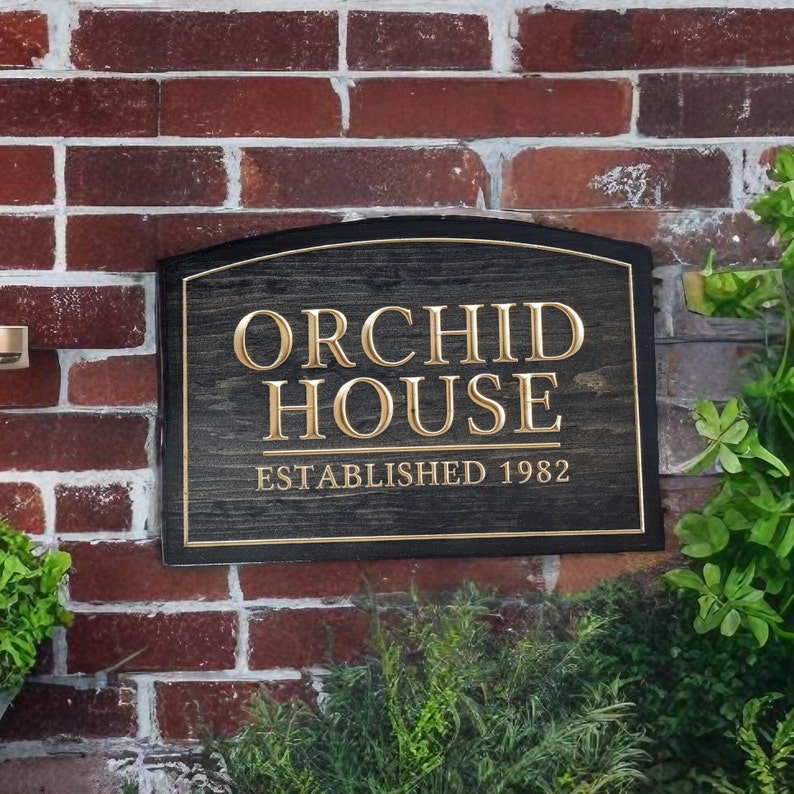 Pu&ograve; includere: Un cartello in legno nero con un'iscrizione dorata che recita "Orchid House Established 1982". Il cartello &egrave; montato su un muro di mattoni.