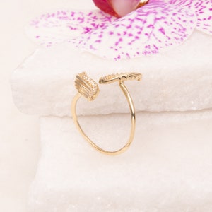 May include: A gold ring with a delicate wing design. The ring is set with small, clear stones.