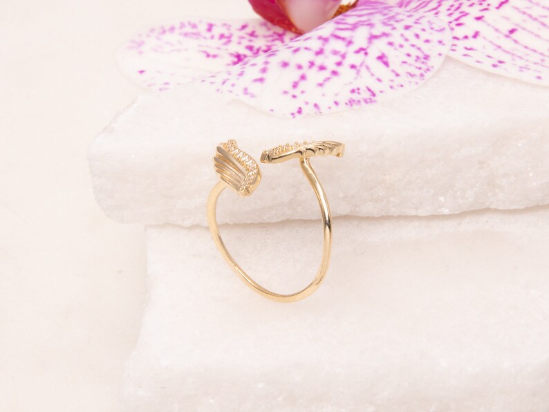 May include: A gold ring with a delicate wing design. The ring is set with small, clear stones.