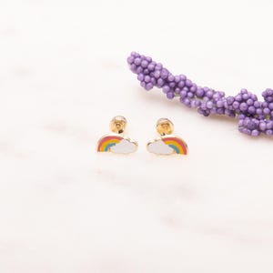 May include: A pair of gold-tone rainbow and cloud stud earrings. The earrings are small and delicate, perfect for a child.