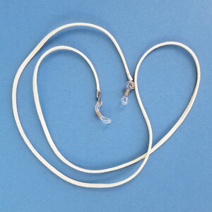 May include: White leather eyeglass chain with silver metal clasps. The chain is looped and ready to be worn.