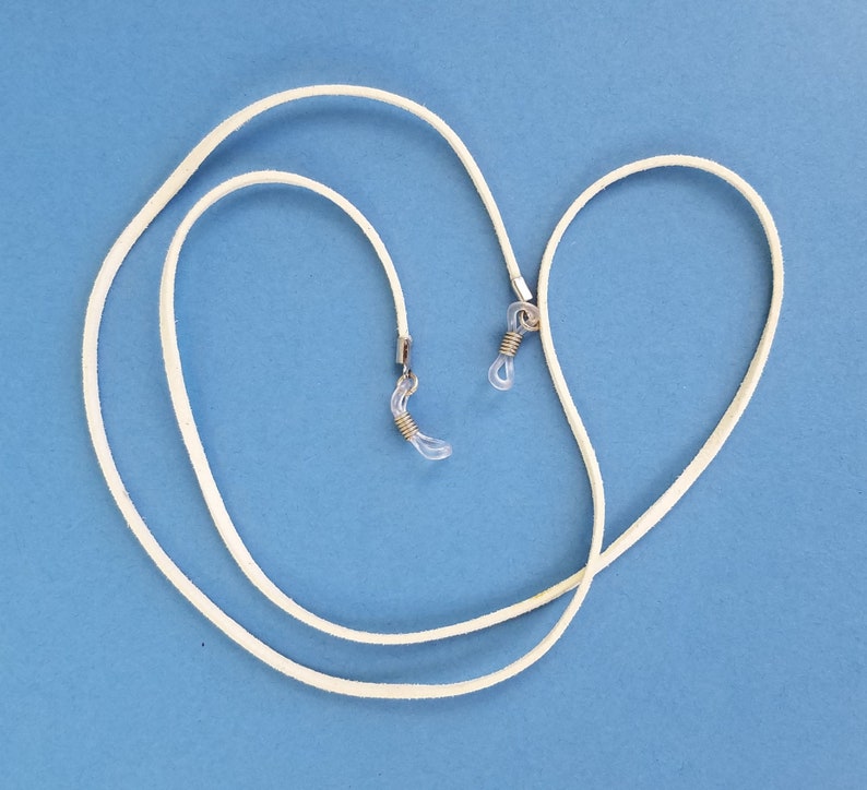 May include: White leather eyeglass chain with silver metal clasps. The chain is looped and ready to be worn.