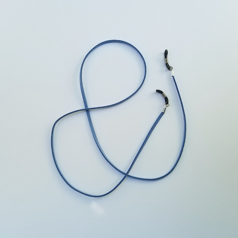May include: A blue eyeglass chain with silver clasps. The chain is made of a thin, flexible material and is designed to hold eyeglasses securely around the neck.