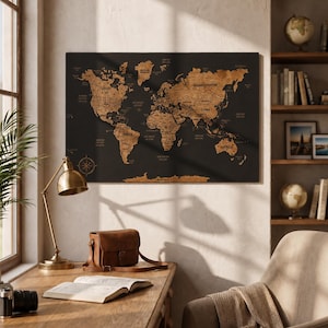 Puede incluir: Un mapa de pared rectangular con fondo negro y continentes e islas en relieve en tonos de madera natural. El mapa incluye nombres de países grabados, etiquetas de océanos y una rosa de los vientos en la esquina inferior izquierda.