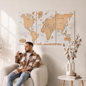 Puede incluir: Un conjunto de tres paneles de pared con un mapa del mundo de madera, con continentes cortados a láser en un acabado de madera clara sobre fondos rectangulares blancos, mostrando etiquetas geográficas en texto negro.