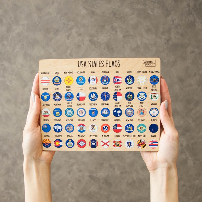 May include: Wooden puzzle featuring the flags of the USA states. The puzzle has a light wood finish and includes the names of the states. The flags are displayed in a circular design.