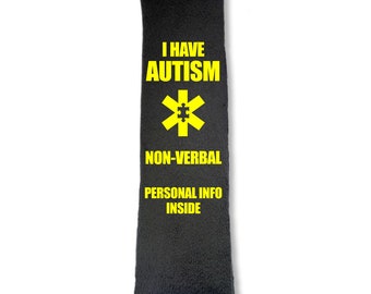 May include: Black car seat belt cover with yellow text that reads "I have Autism, Non-Verbal, Personal Info Inside" and a yellow star of life symbol with a puzzle piece in the center.