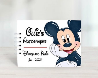 Könnte beinhalten: Ein weißes Autogrammbuch mit einer Schwarzweißillustration von Mickey Mouse. Das Buch trägt den Titel "Ollie's Autographs Disneyland Paris Jan - 2024".