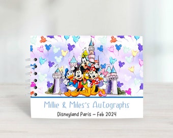 Puede incluir: Un libro de autógrafos blanco con una ilustración colorida de Mickey Mouse y sus amigos frente a un castillo con globos. El texto en la portada dice "Millie & Miles's Autographs Disneyland Paris - Feb 2024".