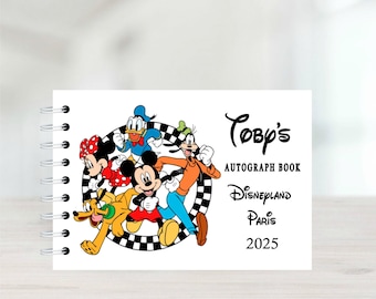 Könnte beinhalten: Weißes Spiral-Notizbuch mit Mickey Mouse, Minnie Mouse, Donald Duck, Goofy und Pluto. Auf dem Cover steht "Toby's AUTOGRAPH BOOK Disneyland Paris 2025" in schwarzer Schrift.