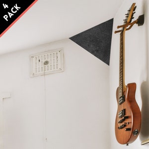 May include: A wooden electric guitar hangs on a wall-mounted guitar holder. The guitar has a brown finish and black hardware. A black triangle is painted on the wall. The text "4 PACK" is in the upper left corner.