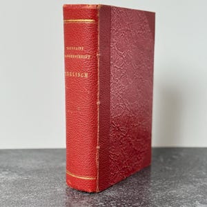 May include: A vintage red book with gold lettering and accents. The book's spine features the title "TOUSSAINT JABORNCHREIDE ENGLISCH". The cover has a textured, leather-like appearance, and the edges are slightly worn.