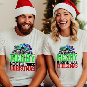 Puede incluir: Dos camisetas blancas con un gr&aacute;fico de cami&oacute;n monstruo verde y el texto "Merry Monster Truck Christmas". Las camisetas las llevan dos personas con gorros de Pap&aacute; Noel.