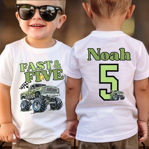Pictured is a boy wearing a white t-shirt with a green and black monster truck graphic. The front of the shirt says "FAST & FIVE" in green lettering. The back of the shirt has the name "Noah" and the number "5" in green and a small version of the camo truck