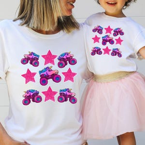 Mom and daughter are wearing matching white t-shirts with 3 rows of pink sparkle stars and sparkle pink smash unicorn monster trucks. Monster Truck Mom shirt, Monster Truck Girl Shirt. Girls Vehicles Truck Shirt. Monster Truck Jam Racing Shirt for Her.