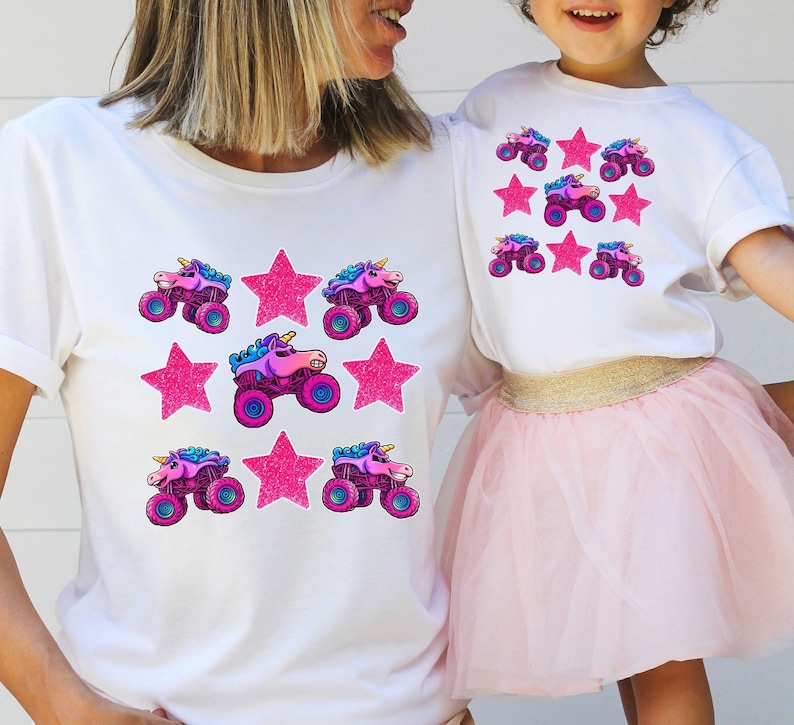 Mom and daughter are wearing matching white t-shirts with 3 rows of pink sparkle stars and sparkle pink smash unicorn monster trucks. Monster Truck Mom shirt, Monster Truck Girl Shirt. Girls Vehicles Truck Shirt. Monster Truck Jam Racing Shirt for Her.