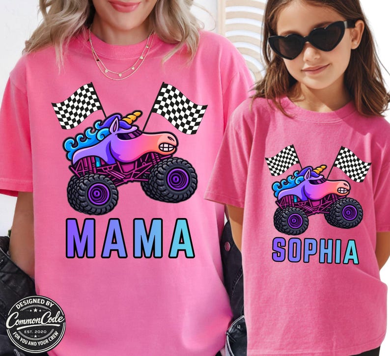 Pictured is Mother and daughter wearing berry pink comfort colors tee's with blue rainbow sparkle smash unicorn monster trucks with 2 black and white checkered flags above custom name MAMA and SOPHIA