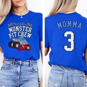 以下が含まれることがあります： グラフィック付きの青いTシャツ2枚。1枚は、サメをテーマにしたモンスターカーで「Noah's Monster Pit Crew Jam」と表示されています。もう1枚は「Momma」と数字の「3」を表示しています。どちらも青いジーンズと組み合わせています。
