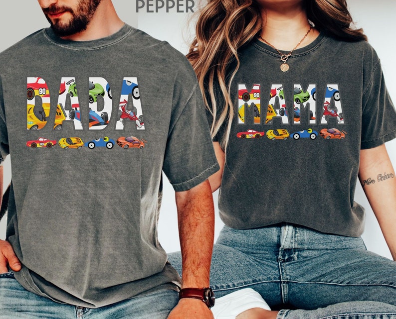 May include: Two gray t-shirts with the words "DADA" and "MAMA" spelled out in colorful cartoon race cars.