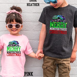 Puede incluir: Dos ni&ntilde;os con camisas de Navidad a juego con un cami&oacute;n monstruo verde y el texto "Feliz Navidad del cami&oacute;n monstruo". La ni&ntilde;a lleva una camisa rosa y el ni&ntilde;o lleva una camisa gris oscuro jaspeada.