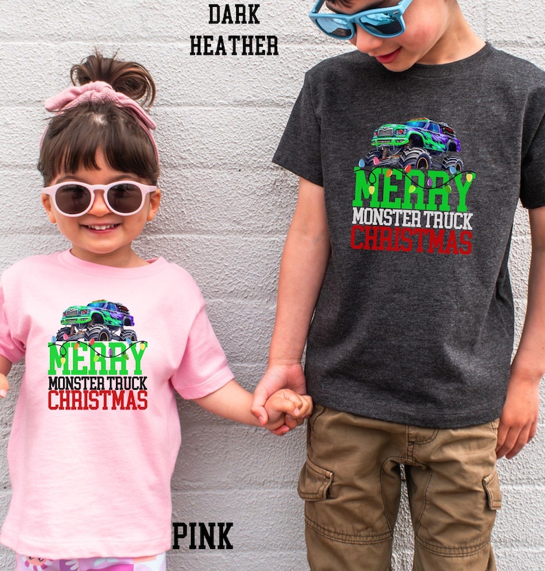 Puede incluir: Dos ni&ntilde;os con camisas de Navidad a juego con un cami&oacute;n monstruo verde y el texto "Feliz Navidad del cami&oacute;n monstruo". La ni&ntilde;a lleva una camisa rosa y el ni&ntilde;o lleva una camisa gris oscuro jaspeada.
