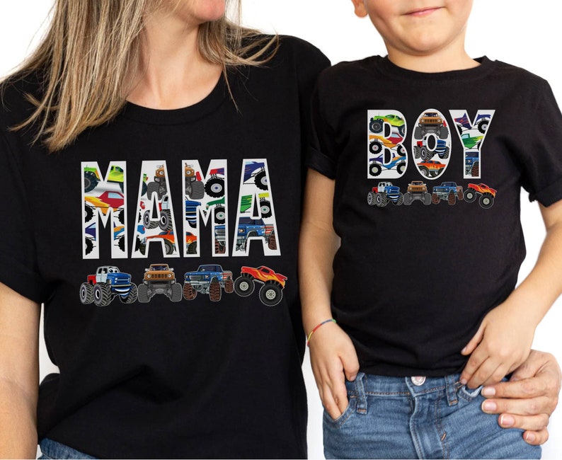 May include: Black t-shirts with matching designs. One shirt says "MAMA" and the other says "BOY", both filled with monster truck graphics. Below each word are illustrations of monster trucks in various colors.