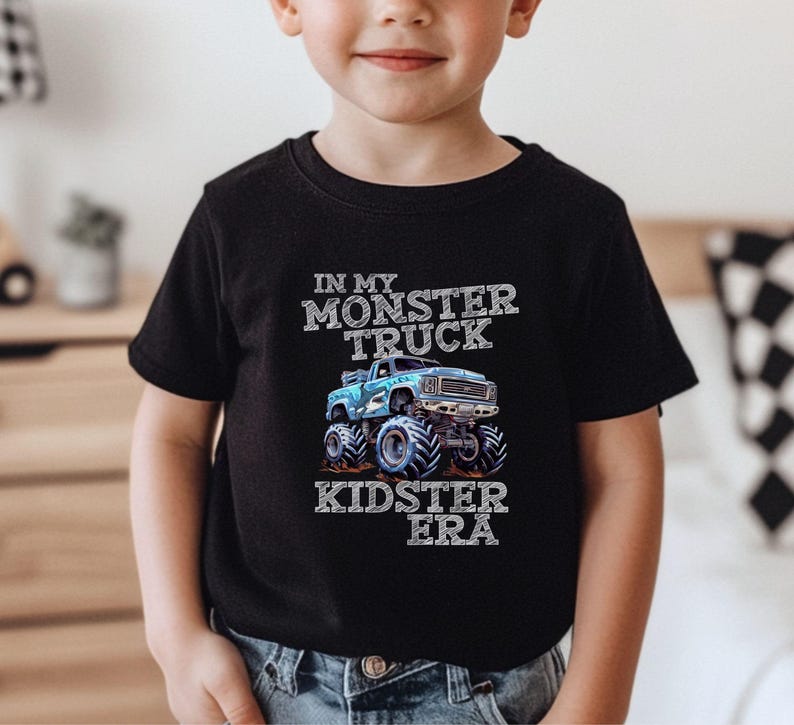Puede incluir: Una camiseta negra con un gr&aacute;fico de cami&oacute;n monstruo azul y el texto "In My Monster Truck Kidster Era".