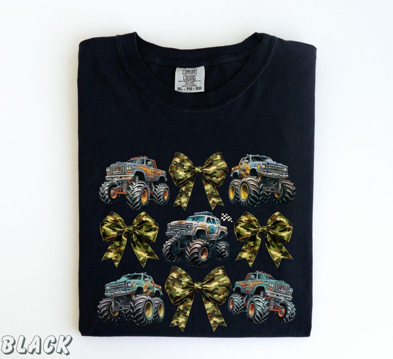 May include: Black t-shirt featuring a design of monster trucks and camouflage bows. The trucks are in various colors, with large tires. The bows are in a camouflage pattern. The text "BLACK" is at the bottom left.