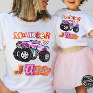 Puede incluir: Camisetas blancas con dise&ntilde;os de monster trucks. Una camiseta dice "Momster Jam" y la otra "Kidster Jam". Los monster trucks son rosas con ruedas negras. Dise&ntilde;ado por Common Code.