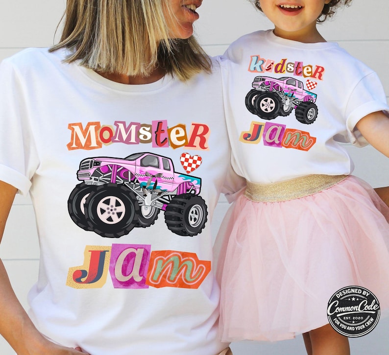 Puede incluir: Camisetas blancas con dise&ntilde;os de monster trucks. Una camiseta dice "Momster Jam" y la otra "Kidster Jam". Los monster trucks son rosas con ruedas negras. Dise&ntilde;ado por Common Code.