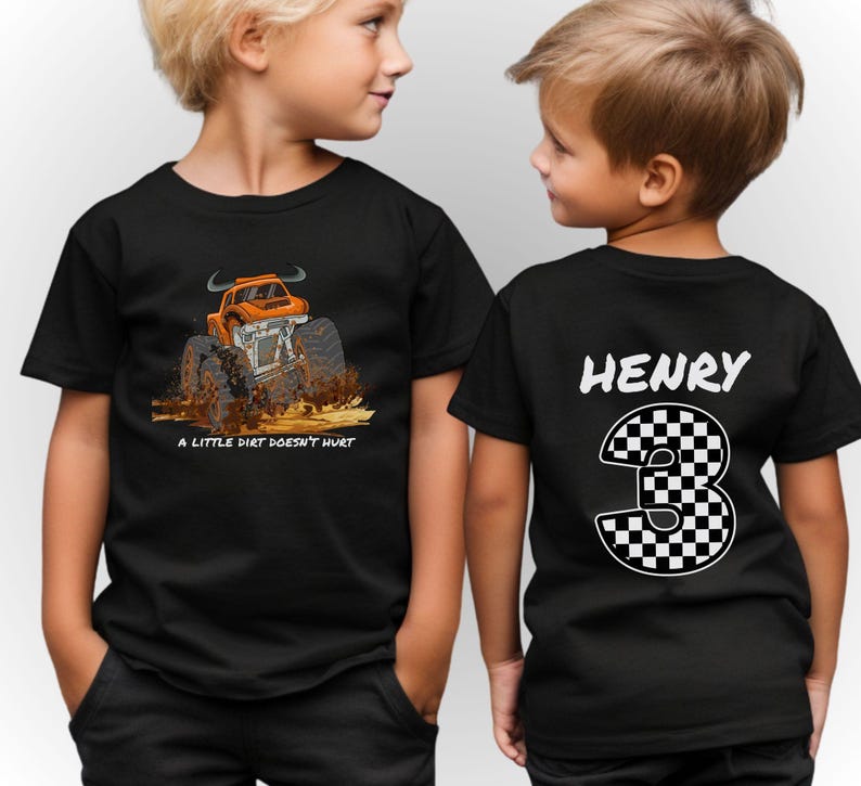 Peut inclure: T-shirts noirs avec un dessin de monster truck et le texte "A Little Dirt Doesn't Hurt". Le dos d'un t-shirt affiche le nom "HENRY" et le chiffre 3 en damier.