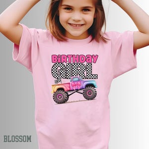 Pode incluir: Camiseta rosa claro com o texto "BIRTHDAY GIRL" em letras rosa e xadrez preto. Um gr&aacute;fico de caminh&atilde;o monstro colorido com um la&ccedil;o rosa &eacute; apresentado abaixo. A camiseta &eacute; de cor rosa claro.